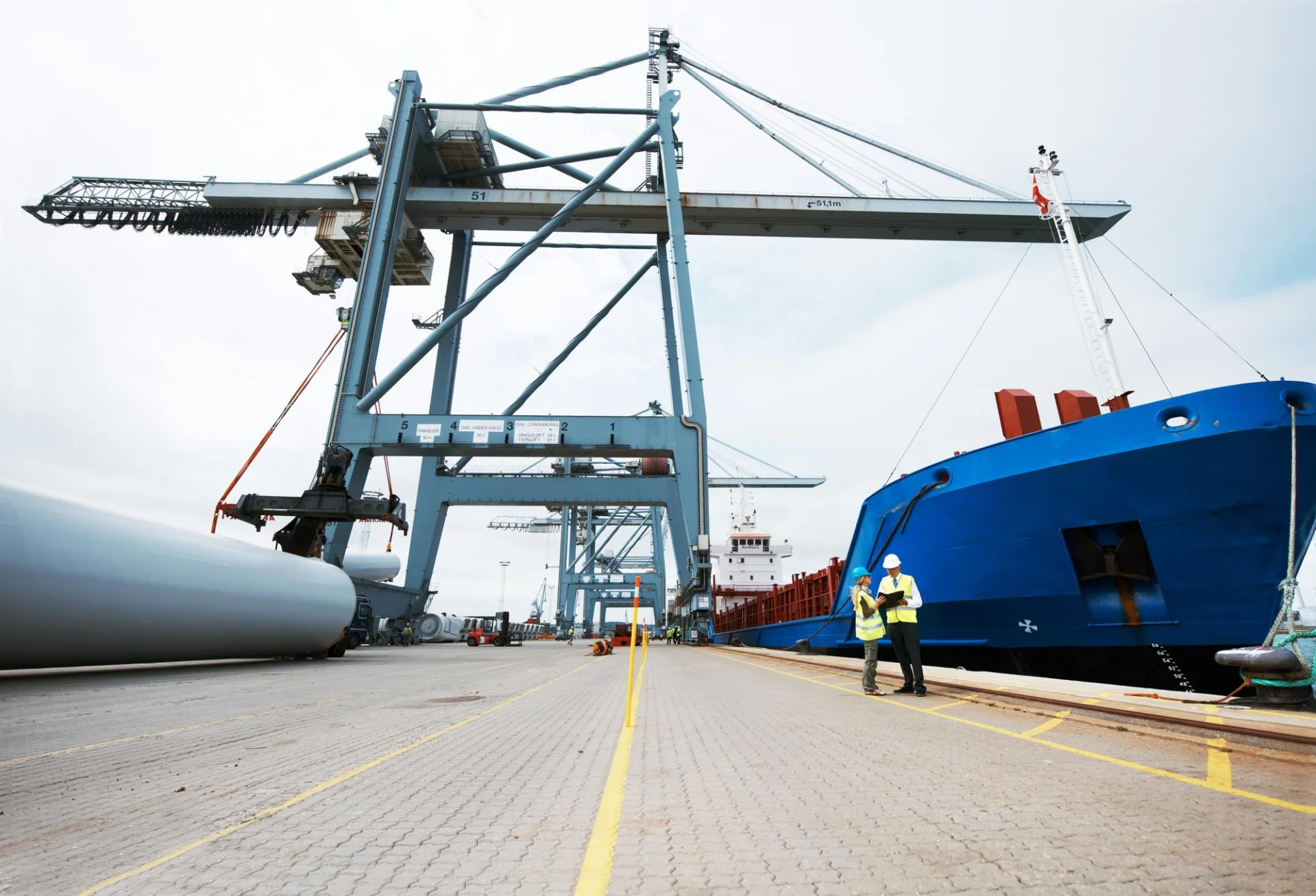 Informácia o stavenisku 6 that makes you larger than life anchored ship dock with cargo being loaded it with cranes two people standing ship